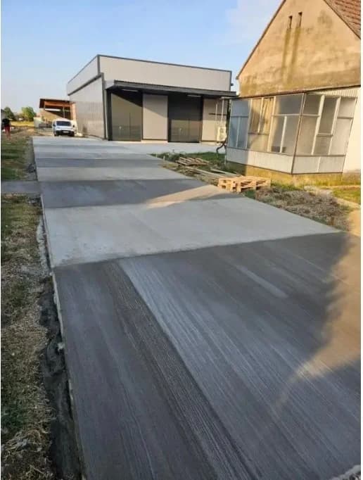 Sveže betonirano dvorište i prilazni put sa metlanom završnom obradom ispred modernog objekta — SB GRADNJA