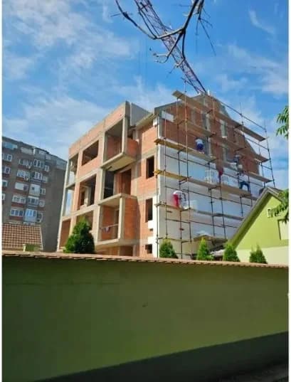 Postavljanje termoizolacije na fasadu stambene zgrade tokom izgradnje — radovi na skeli, SB GRADNJA